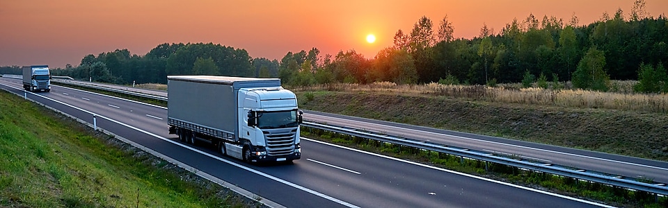 Trucks on a highway at sunset