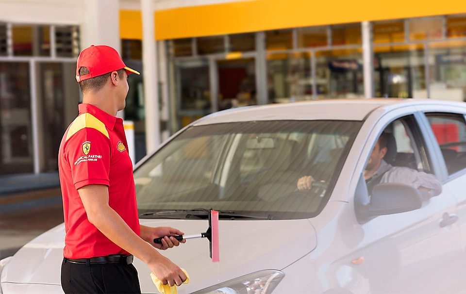 assistant cleaning windscreen of a car